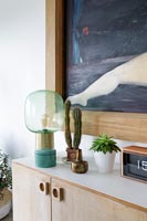 Green lamp and houseplants on modern sideboard 