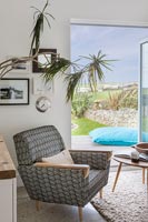 Armchair in living room with open patio doors and coastal view