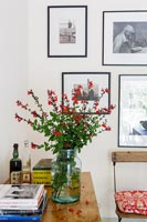 Vase of flowers on table - wall display of framed photographs 