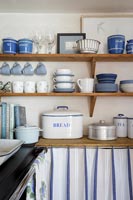 Blue and white crockery on wooden shelf in cottage kitchen