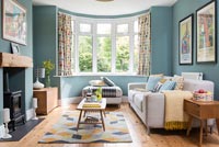 Modern living room with large bay window and teal painted walls 