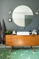 Vintage sideboard with sink in modern bathroom with bright green floor  