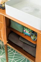 Towels and accessories in vintage sideboard under sink 