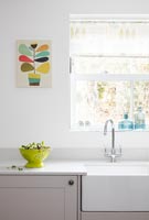 Butler sink and colourful artwork in modern kitchen 