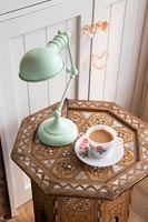 Green lamp and cup of tea on decorative wooden table 