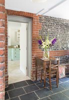 Table and chair in country hallway with exposed stone and brick wall 
