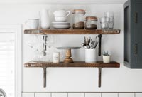 Wooden shelves in kitchen with storage jars and plates 