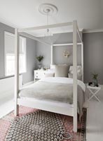 White four poster bed in modern bedroom with grey painted walls 