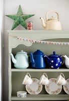 Collection of teapots and crockery on painted green wooden dresser 