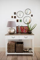 Display of mirrors and small framed pictures above sideboard in hallway 