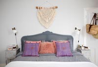 Upholstered grey headboard and cushions on bed 