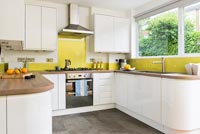 Modern white kitchen with yellow perspex splash backs 