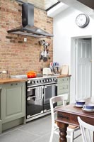 Large range cooker in modern kitchen with exposed brickwork 