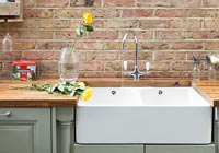 Butler sink in modern kitchen with exposed brickwork 