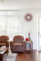 Vintage leather armchairs and sunburst clock in retro living room 