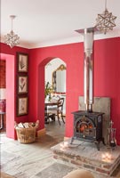Wood burning stove in country living room with red painted walls at Christmas 