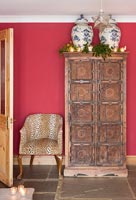 Leopard print covered armchair and vintage cabinet in country living room 