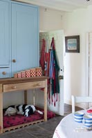 Dog on bed under sideboard and cabinet in country kitchen 