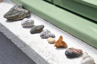 Row of pebbles and stones on exterior windowsill 