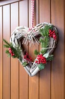 Heart shaped Christmas wreath on wooden door 
