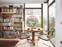 Circular table with chairs in study with bookshelves and large windows 