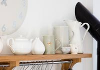 Jugs and teapot on wooden kitchen shelf 