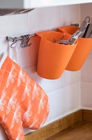 Orange cutlery holders on kitchen wall 
