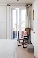Vintage soft toys on rocking chair by French windows in bedroom 
