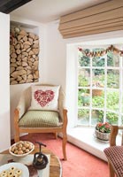 Logs stored in alcove above armchair in cottage living room at Christmas 