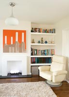Modern living room with leather chair and artwork above fireplace 