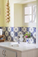 Decorative blue and white tiles behind double sink in kitchen 