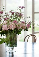 Flower arrangement in vase on wooden dining table 