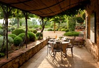 Covered terrace with dining table overlooking formal gardens 