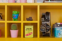 Vintage cine camera and ornaments on bright yellow shelves