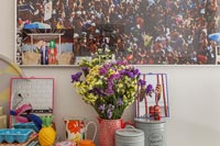 Flower arrangement on kitchen unit with large photograph behind 