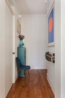 Blue painted cabinet and colourful artwork in hallway 
