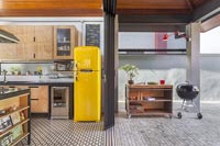 Modern industrial kitchen with open patio doors to barbecue area 