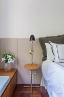 Tiny bedside table and lamp with upholstered headboard wall detail  