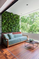 Sofa on decked balcony outdoor living space and green living wall 