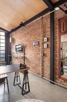 Modern industrial dining area with exposed brickwork wall 