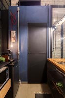 Painted door at one end of tiny industrial kitchen