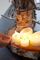 Hand lighting candles on natural wooden base 