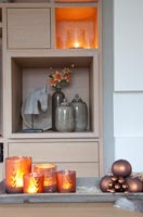 Candles and Christmas baubles on modern wooden furniture 