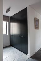 Closet in hallway with black painted doors 