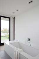 Bath in white bathroom with black framed windows 