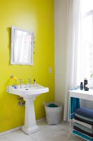 Bright yellow painted feature wall behind bathroom sink 