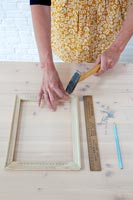 Crafting accessories on table - woman hammering nail into wooden frame 