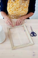 Crafting accessories on table - woman attaching thread to wooden picture frame