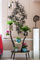 Pink painted wall with black sculpture and vintage plant stand 