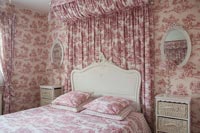 Pink and white bedroom with fabric canopy and wallpaper 